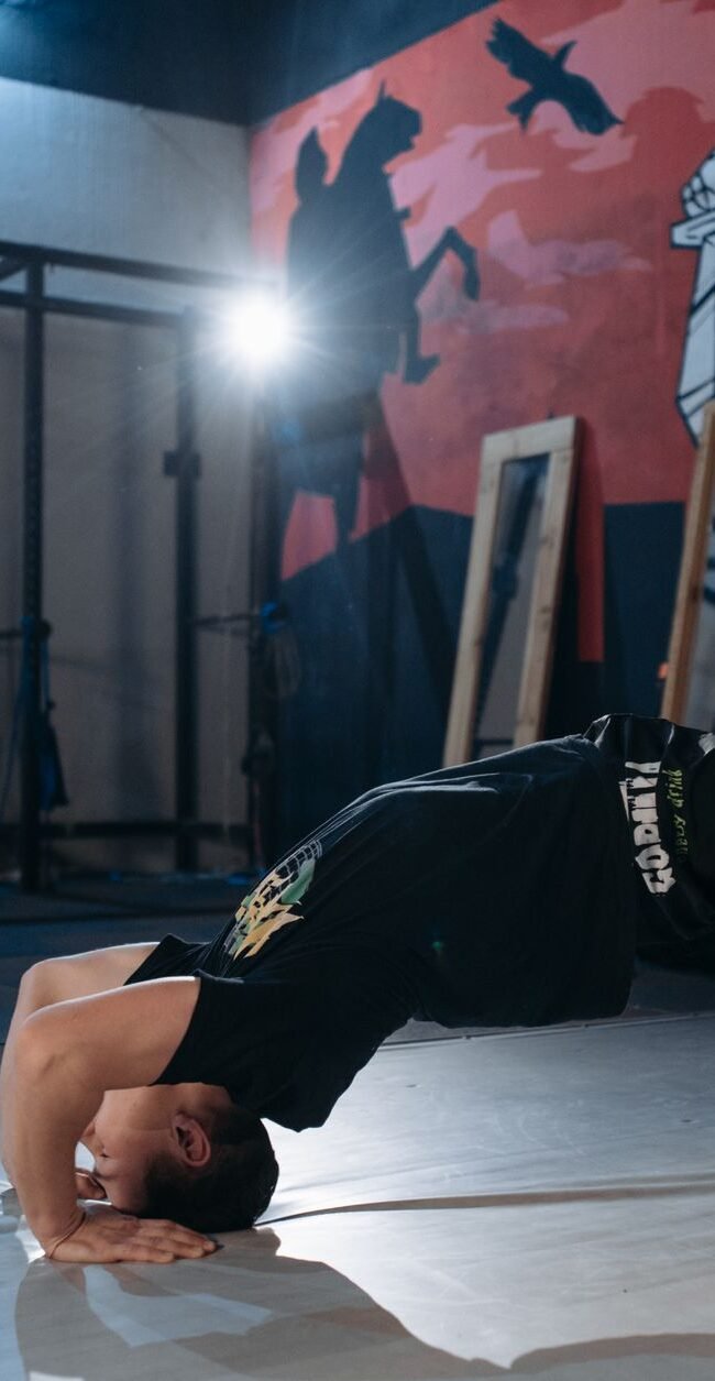 Man performing a back bridge stretch in a gym, emphasizing flexibility and fitness.