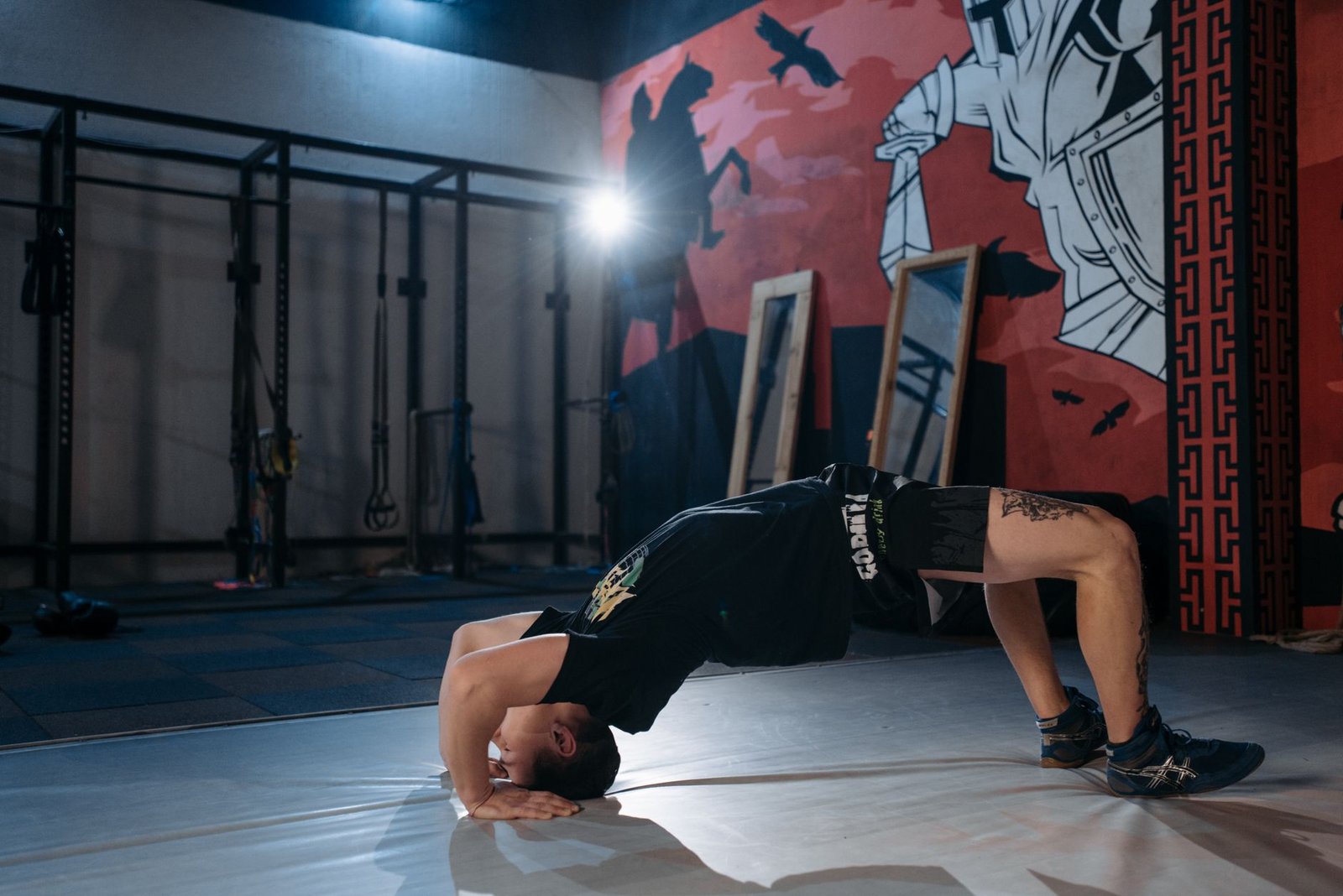 Man performing a back bridge stretch in a gym, emphasizing flexibility and fitness.
