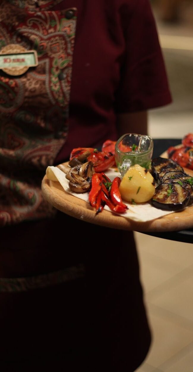 Waitress presenting delicious grilled vegetarian dishes in a restaurant setting.