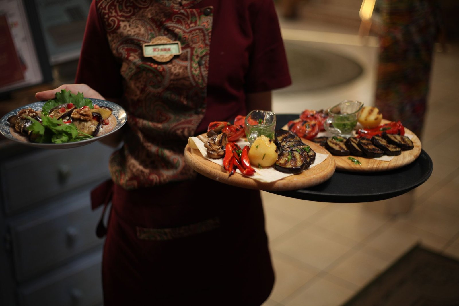 Waitress presenting delicious grilled vegetarian dishes in a restaurant setting.