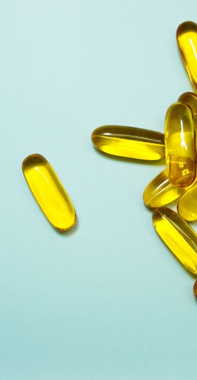 A collection of omega-3 capsules on a light blue surface, ideal for health and supplement themes.