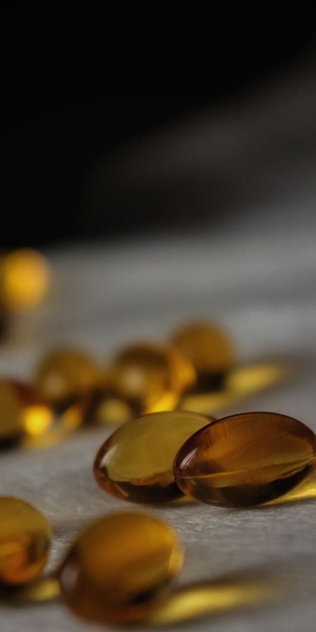Close-up of golden soft gel capsules with a dark blurred background.