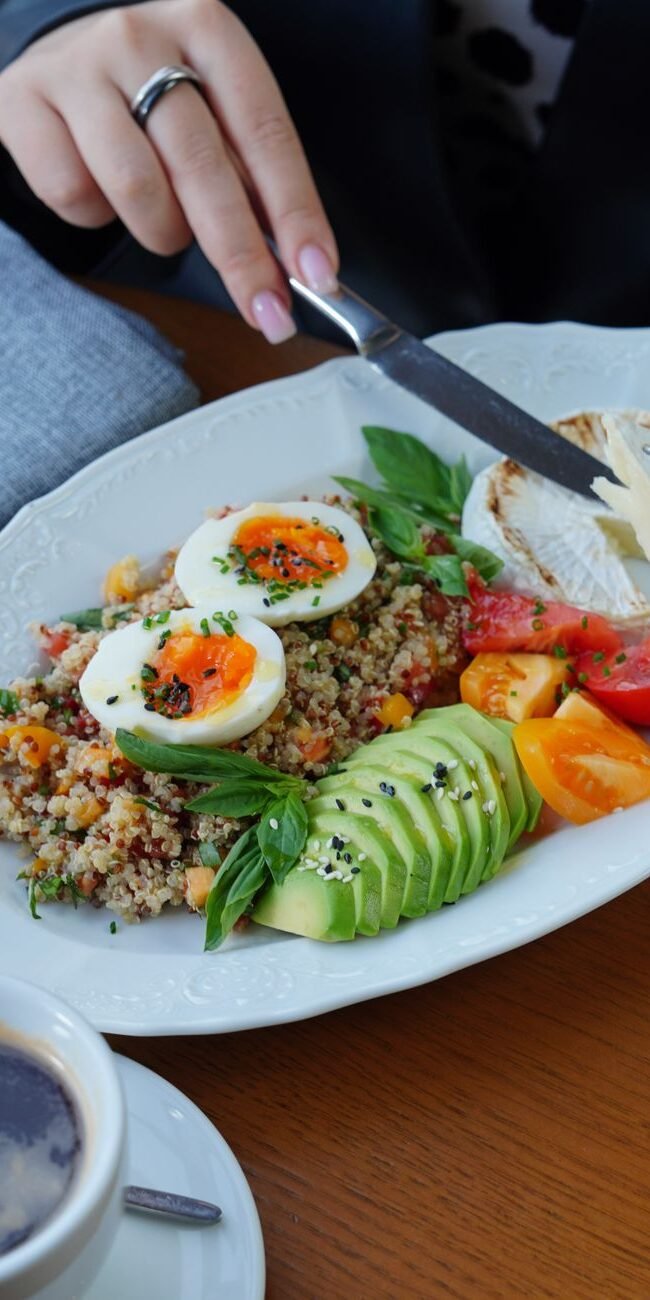 A delicious and healthy breakfast featuring avocado, eggs, and coffee served on a wooden table.