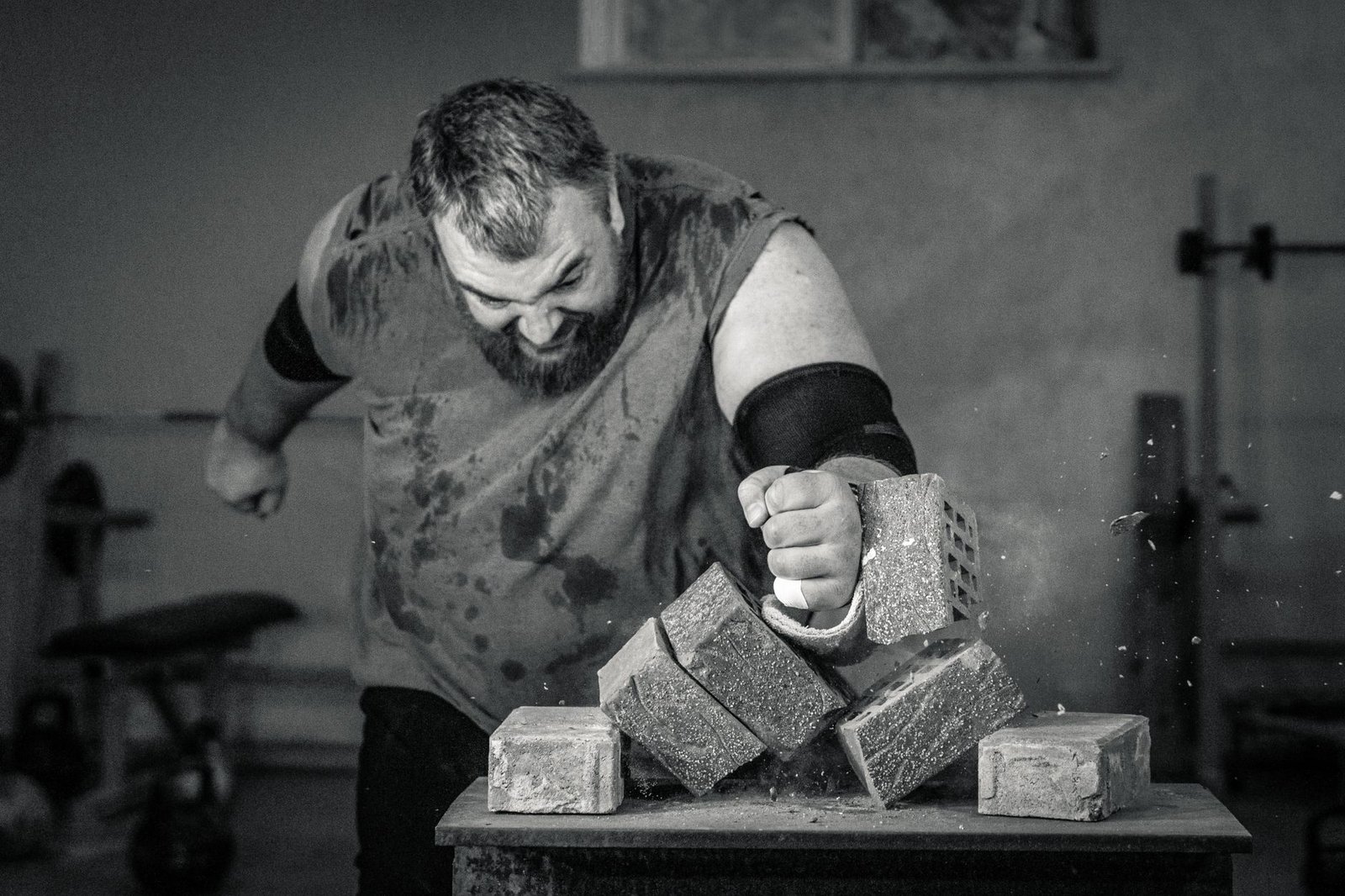 A powerful image of a strongman smashing concrete blocks with his fist, showcasing strength and determination.